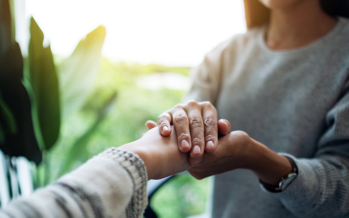 Women holding each other hands for comfort